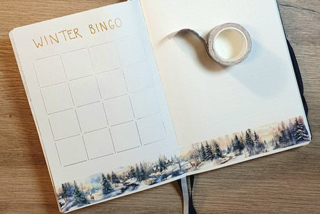 Uppslagen Bullet Journal med pÄbörjad bingo. Vintertema pÄ washi tape i boken.