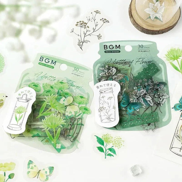 Förpackningar med flake stickers i serien Flower blooms in a bottle. Klistermärken med blommor ligger utspridda runt. - Tidformera