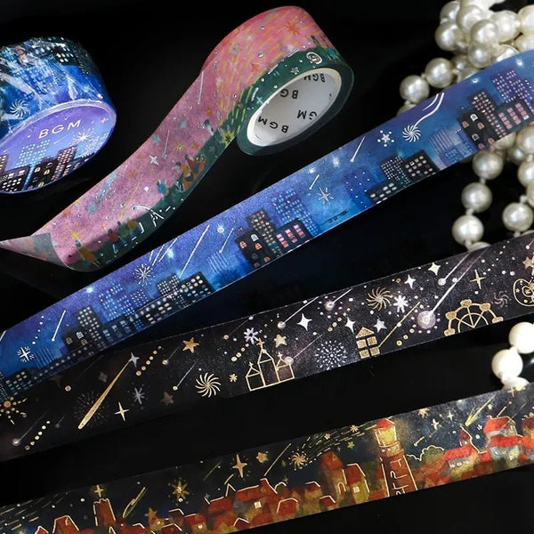 Serier - Night of shooting stars från BGM. Flera rullar med washi tape ligger utrullade på ett bord. Motiven på är natthimmel med stjärnfall. Bredvid ligger ett pärlhalsband.