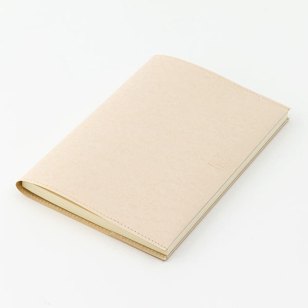 Serier - Notebook cover Midori - Skrivbok med cremefärgat bokomslag ligger på en vit yta - Tidformera