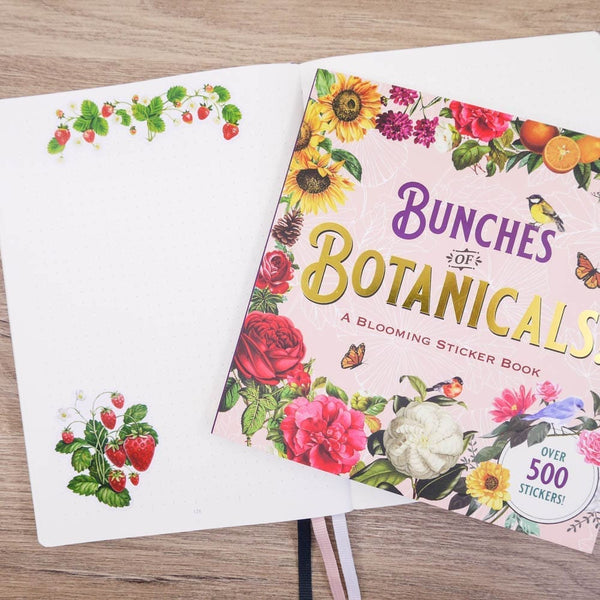 Peter Pauper Sticker book Bunches of Botanicals ligger på en öppnad anteckningsbok där stickers med jordgubbar syns. - Tidformera