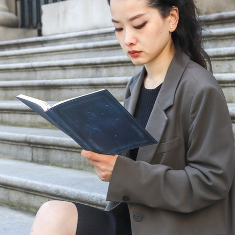 Kvinna på en trappa som kollar i sin blåa Inkblot Business Planner från Paperblanks.