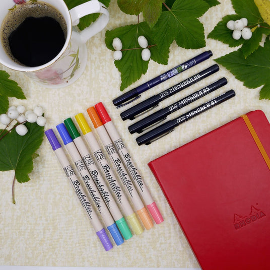 Olika former av pennor till Bullet journaling med en röd anteckningsbok.