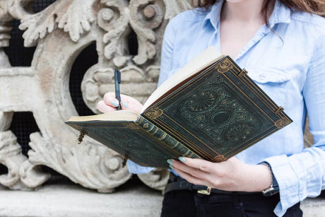 Kvinna som skriver i sin anteckningsbok Nocturnelle Grande Linjerad från Paperblanks - Tidformera