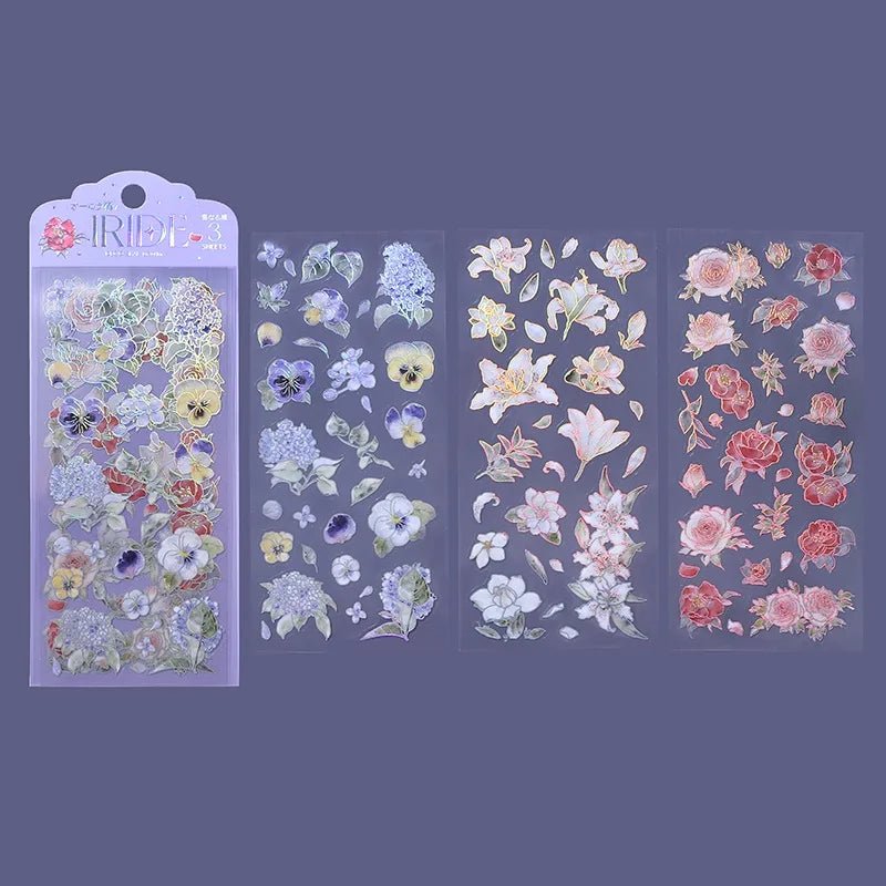 Clear stickers IRIDE 3-pack - Flower Blooming från BGM. Förpackning med klistermärken och bredvid ligger tre ark med stickers. Motiv med hortensia, penseer, löv, liljor och rosor.
