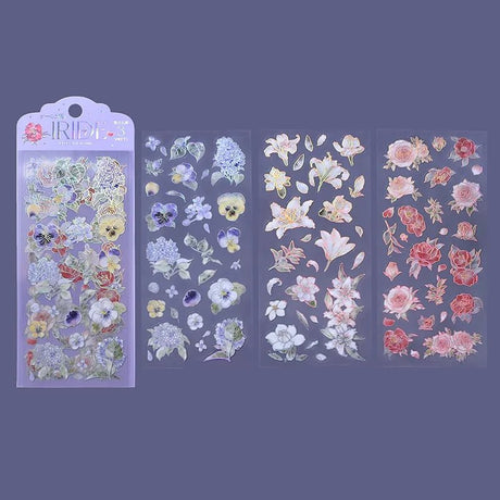 Clear stickers IRIDE 3-pack - Flower Blooming från BGM. Förpackning med klistermärken och bredvid ligger tre ark med stickers. Motiv med hortensia, penseer, löv, liljor och rosor.