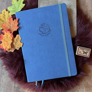 Dotted Notebook B5 160 GSM - Globe från Paper24. Blå anteckningsbok med motiv med en hand som håller i en jordglob. Bredvid är det lönnlöv. - Tidformera