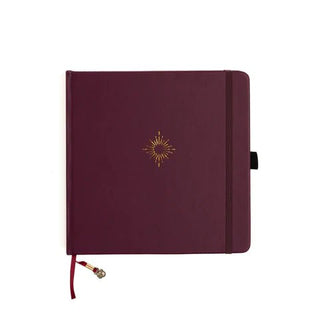 Mörkröd kvadratisk anteckningsbok med guldfärgat motiv med polstjärnan. Dotted Notebook Northstar SQ från Archer & Olive.