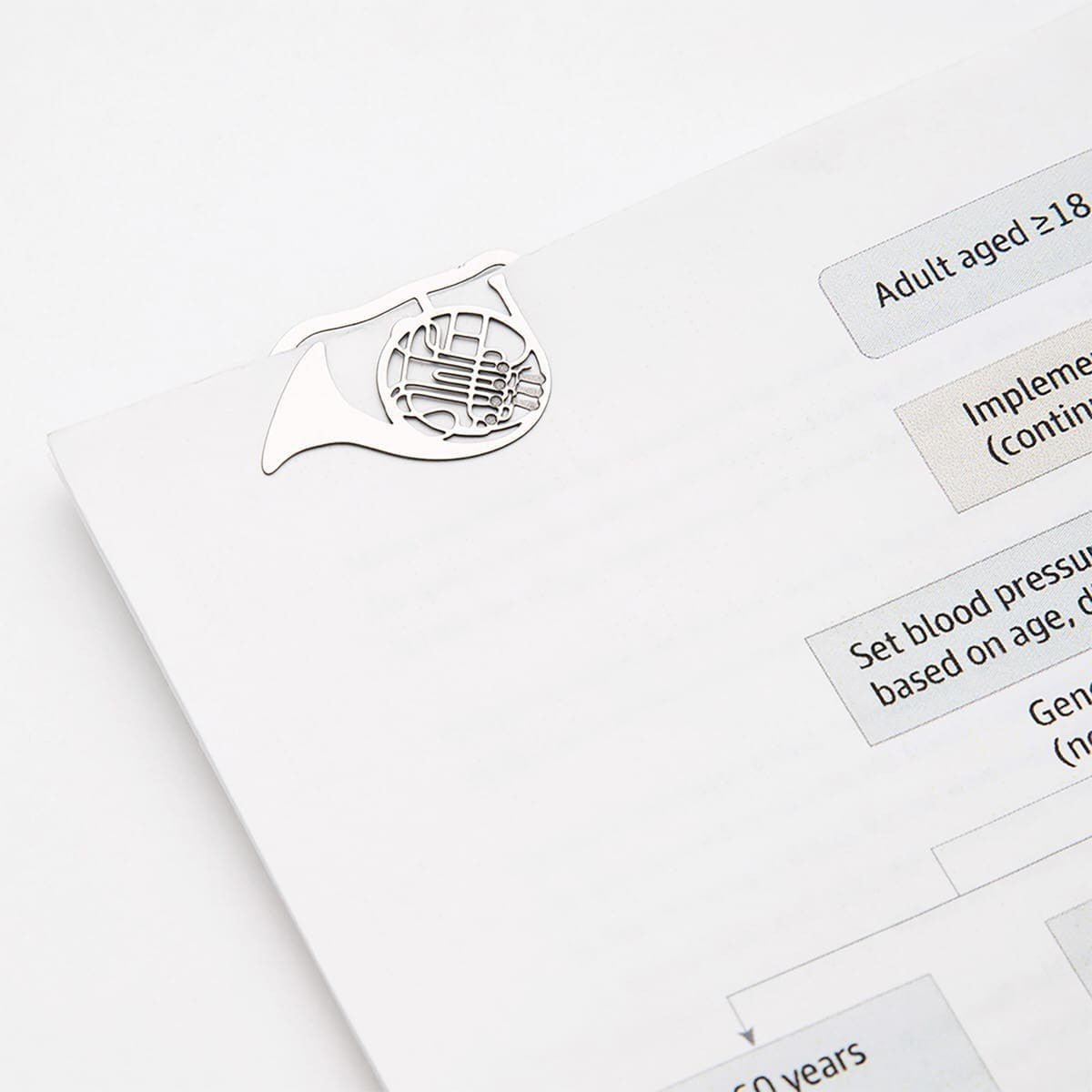 E - clips Gem i metall - Musical instruments från Midori - En bok som har ett gem insatt på en sida. Gemet har motiv med ett blåsinstrument.  Tidformera