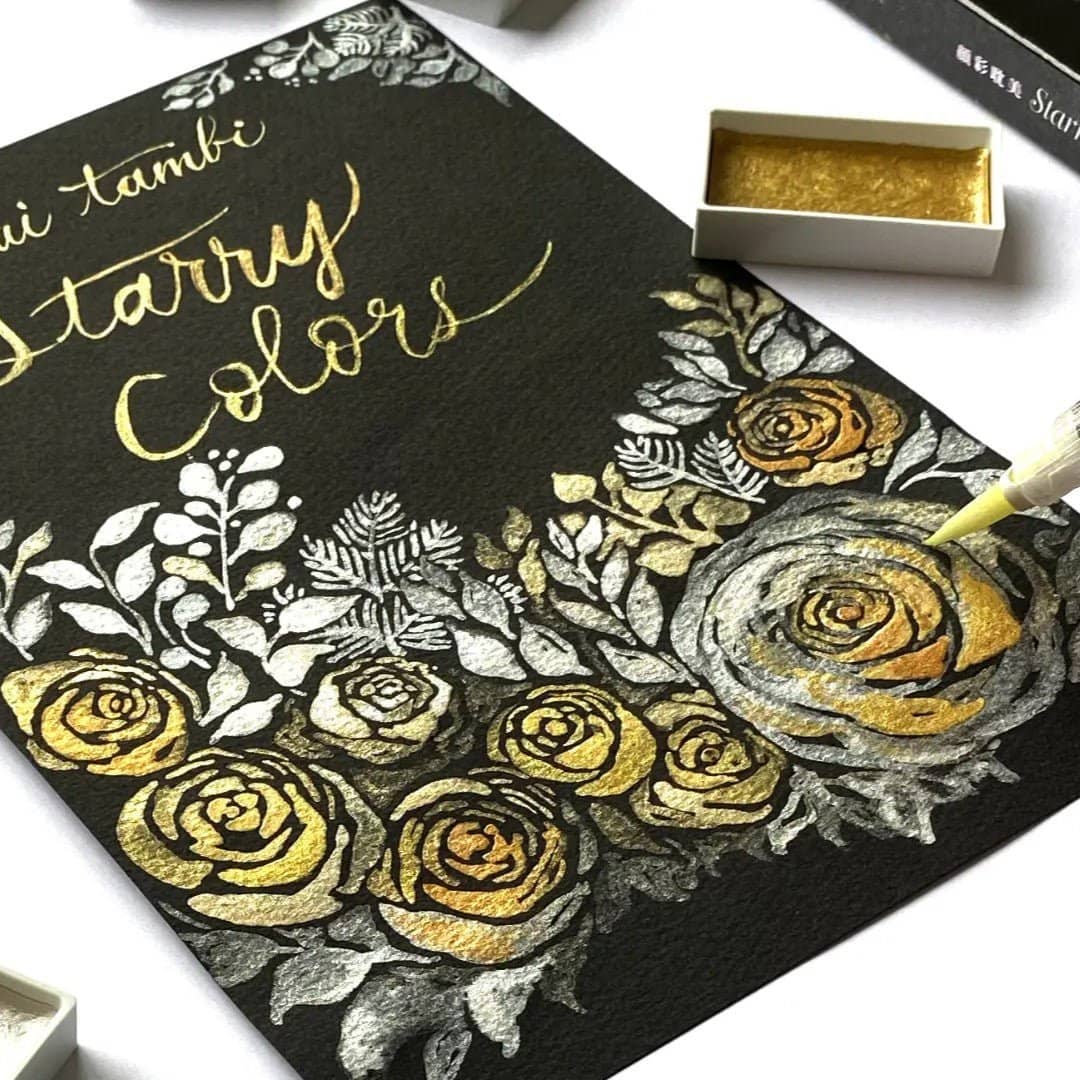 Guld och silver blommor och text målat på svart papper med Gansai Tambi akvarellfärger.