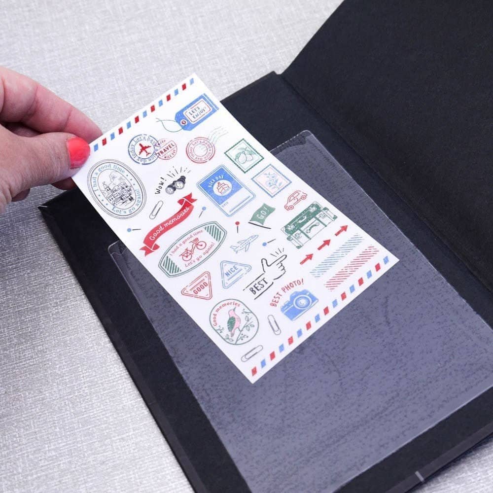 Självhäftande istoppsfickor A6 Pockets från 3L. En hand skjuter in ett ark i en plastficka som är fäst i en skrivbok.  Tidformera