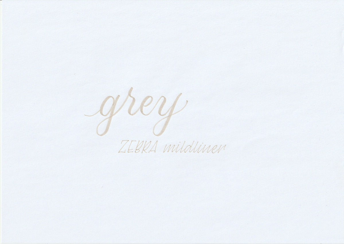 Handskriven text med orden "grey" och "ZEBRA mildliner" i grå färg, skriven med Zebra Mildliner Brush Pen i färgen Grey.