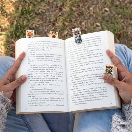 Små bokmärken i trä med personifierade djur. Bokmärken är fästa på uppslagen bok.Wooden Booktags - Book friends från Cozywood - Tidformera