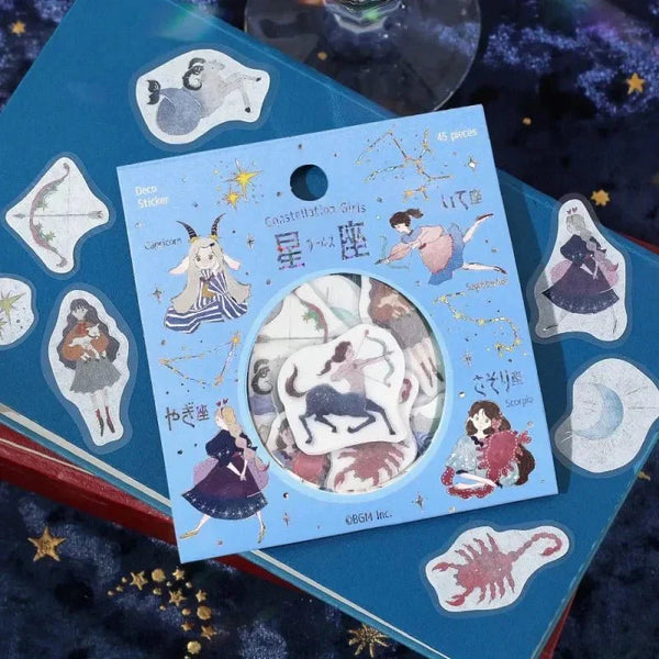Förpackning med Flake stickers Constellations från BGM ligger på ett bord. Stickers med stjärntecken är utströdda.  Tidformera