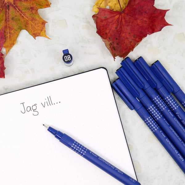Fineliners Drawing pen från Pilot Pen ligger vid en uppslagen anteckningsbok, omringat med höstlöv. - Tidformera
