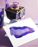 Öppnad flaska med färgprov på ila bläck med gnistrande guldeffekt Bläckflaska J. HERBIN INK 50 ml - 1670 Violet Impérial från Herbin - Tidformera