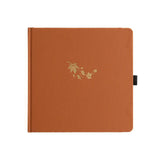 Orange kvadratisk anteckningsbok. Guldpräglat med fallande lönnlöv på pärmen
Dotted Notebook Swirling Leaves SQ -  - Archer & Olive - Tidformera