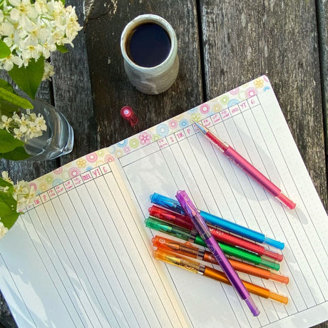 Gelkulpenna Maica - Orange från Pilot Pen. Sju stycken pennor av märket Maica i olika färger. Pennorna ligger på en anteckningsbok som är uppslagen. I skrivbok har pennorna använts för att skriva. Tidformera