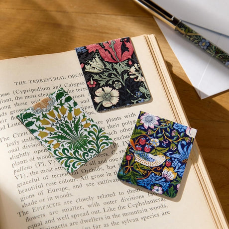 Magnetic bookmarks - William Morris från Galison. Tre bokmärken med William Morris motiv, en sitter insatt i en läsebok och de andra två ligger bredvid.  - Tidformera