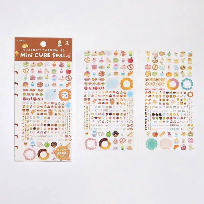 Planner Stickers Sheet 2-pack - A Bite of Sweets från BGM. Förpackning med klistermärken och bredvid är två ark med sticker med motiv med kakor, bakelser, frukter och drycker. - Tidformera