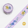 Lila dekorationstejp med blommor i blått och gult. Motivet ser ut som broderi. Washi Tape Embroidered Ribbon - Sumire från BGM - Tidformera