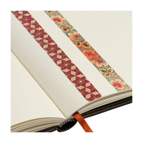 Washi Tape Paperblanks 2 - pack - Hishi & Filigree Floral Ivory från Paperblanks. I en anteckningsbok är det två washitejp fastsatta. En har rött stjärnmönster och den andra är blommig. - Tidformera