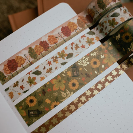 Höstmotiv med träd och löv på dekorationetejp. Tejpen är utdragen på en sida i en anteckningsbok. Washi tape - Swirling Leaves - 4 - pack - från Archer & Olive - Tidformera